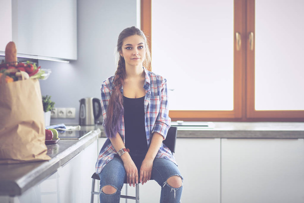 Young woman sitting near table in the kitchen - Fotoğraf, Görsel
