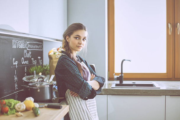 Giovane donna in piedi vicino al fornello in cucina - Foto, immagini