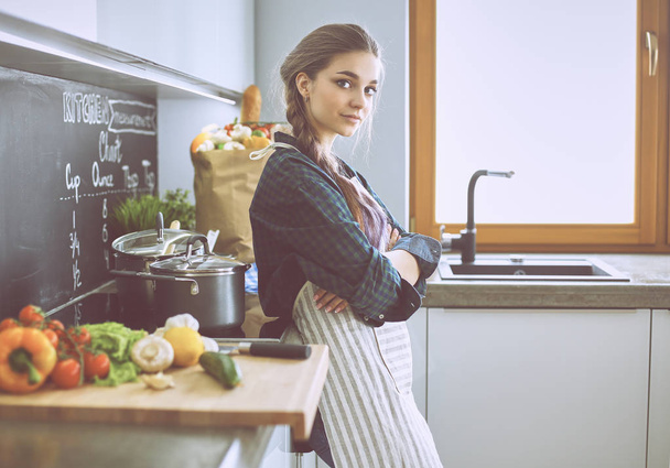 Jovem mulher em pé junto ao fogão na cozinha - Foto, Imagem
