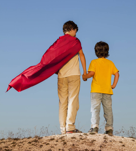 Two boys playing superheroes on the sky background - Foto, afbeelding