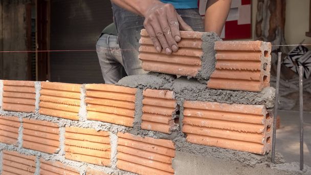 Trabajador albañil instalando mampostería de ladrillo en la pared exterior
 - Foto, Imagen