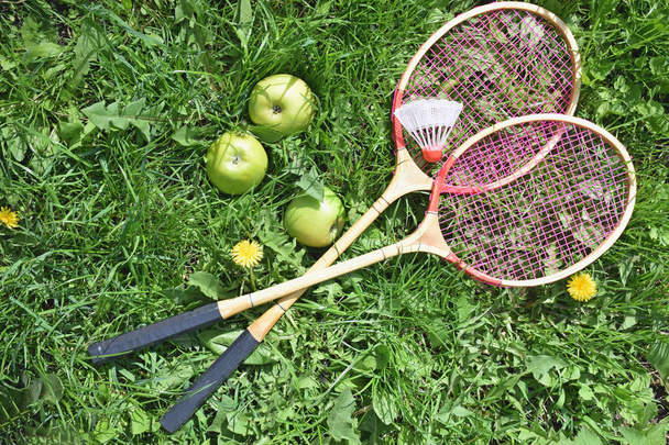 Badminton rackets on the green grass, and green apples .Excellen - Photo, image