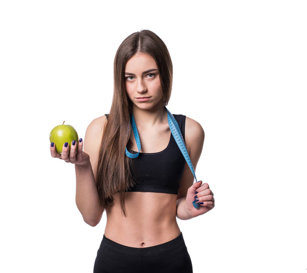 Slim and healthy young woman holding measure tape and apple isolated on white background. Weight loss and diet concept. - 写真・画像