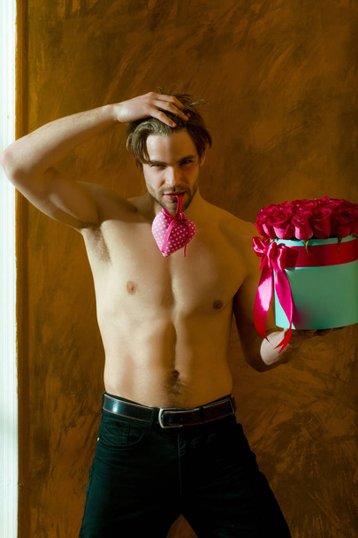 bearded muscular man with sexy body holds red rose box - Foto, imagen