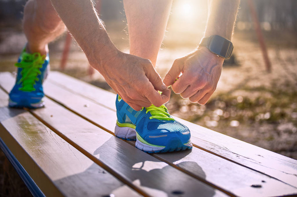 Завязывать шнурки на кроссовках во время занятий спортом на открытом воздухе
. - Фото, изображение