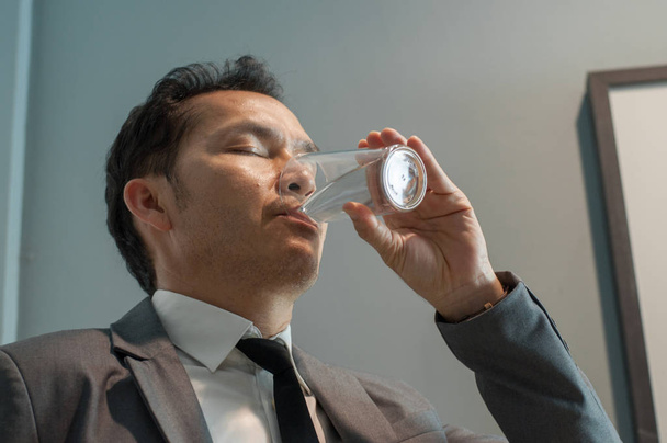 Asian Businessman in grey suit drinking water. Healthy. Copy spa - 写真・画像