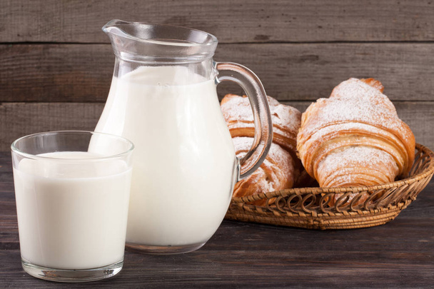 jug and glass of milk with croissants on a wooden background - Photo, image