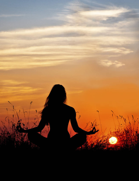 Silhouet van de vrouw in lotus meditatie op zonsondergang achtergrond. Yoga. - Foto, afbeelding
