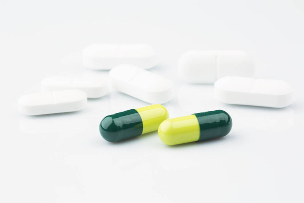 Green capsules and white antibiotic pills. - Foto, Imagem