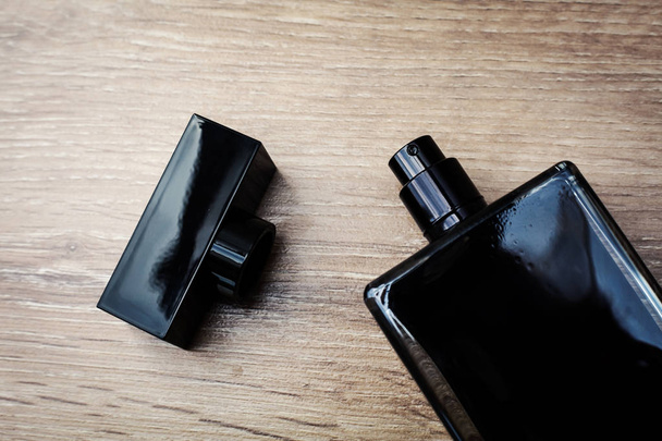Black bottle of pefume in wooden background - Фото, изображение