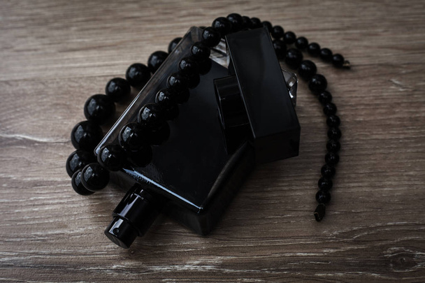 perfume with black beads in wooden background - Zdjęcie, obraz