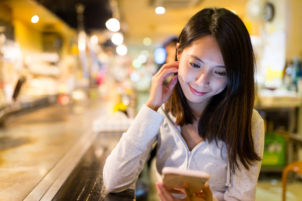Femme lisant les nouvelles sur le téléphone portable dans le restaurant
 - Photo, image