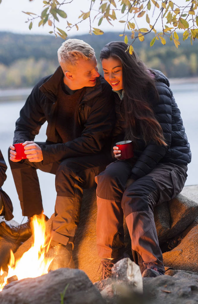 Paar mit Kaffeetassen am Lagerfeuer - Foto, Bild