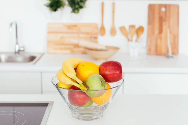 Φρέσκα φρούτα σε ένα γυάλινο μπολ σε μια κουζίνα - Φωτογραφία, εικόνα