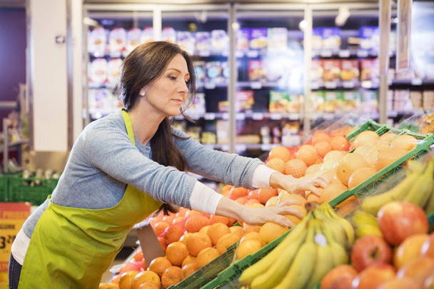 Saleswoman Arranging Oranges In Supermarket - Foto, Imagen