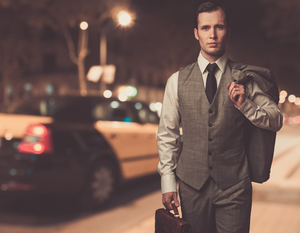 Man in classic grey suit with briefcase walking outdoors at night - Photo, Image