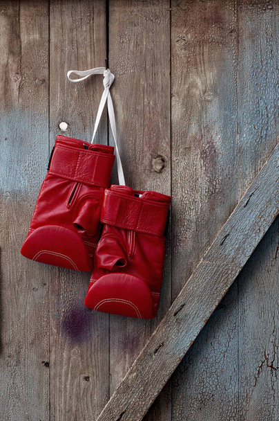  Paire de gants de boxe en cuir rouge suspendus à un clou
  - Photo, image