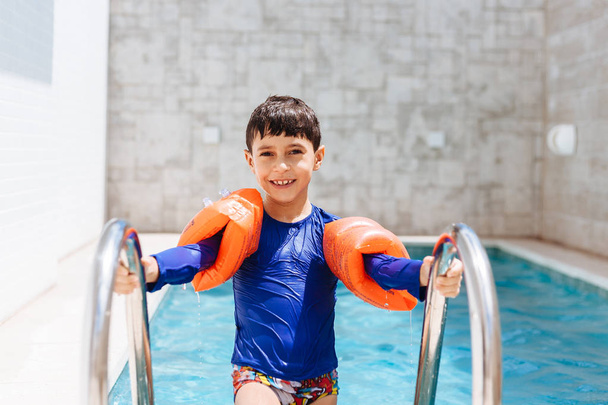Sweet little boy in swimsuit with arm float in the pool - Фото, изображение
