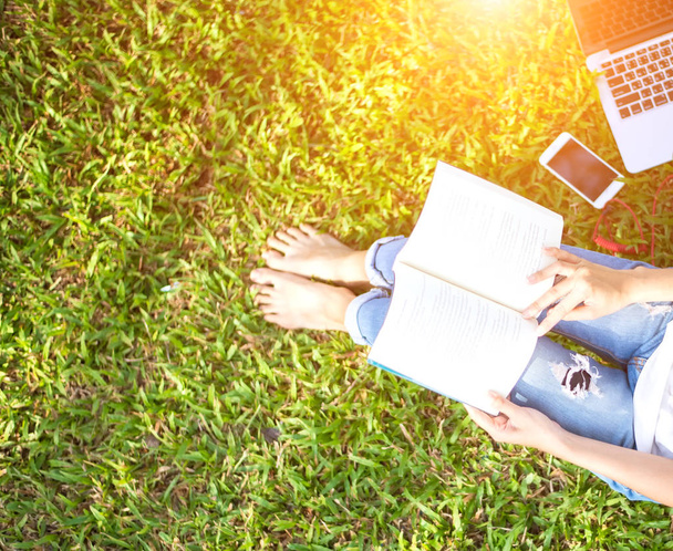 Dziewczyna lektura książki i grać laptopa na trawie, złożony z parku w rano, odcień zieleni 2017 - Zdjęcie, obraz