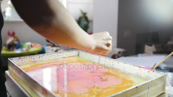 Process of painting - purple paint drops on yellow background - woman draws on water in Liquid Ebru art technics - Footage, Video
