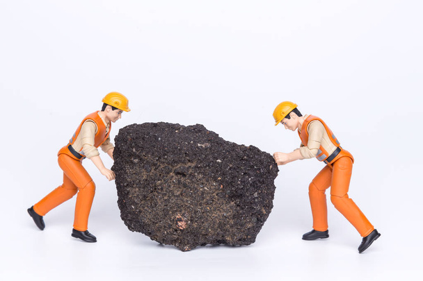 Los trabajadores de juguetes en miniatura tirando de una gran roca
 - Foto, imagen
