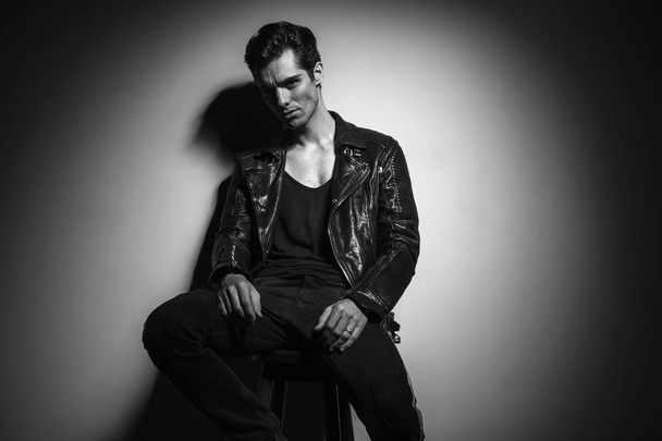 man in leather jacket sitting and leaning against  wall - Photo, Image