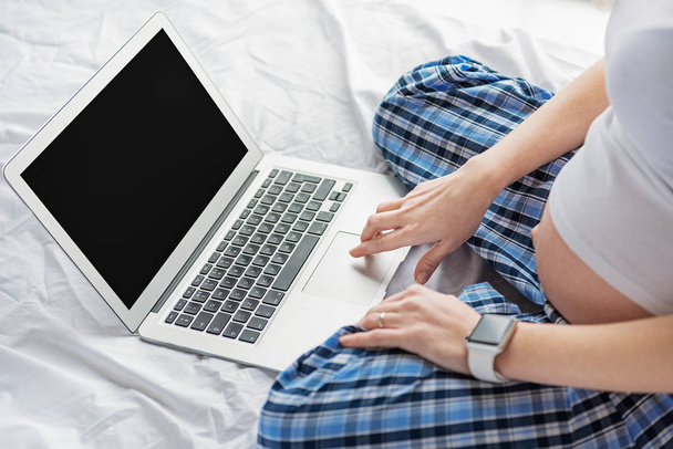 Pregnant woman enjoying laptop in bedroom - Фото, зображення