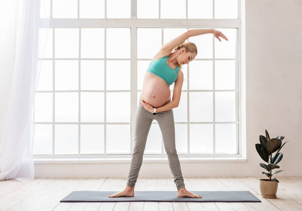 Mulher grávida bonita se envolver em pilates em casa
 - Foto, Imagem