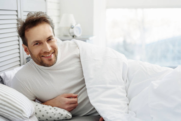 Happy guy relaxing in bedroom - Photo, Image