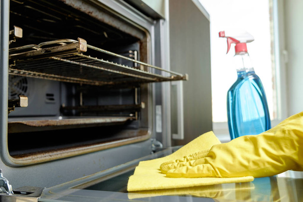 Man with bottle of spray and rag cleaning oven - Foto, immagini