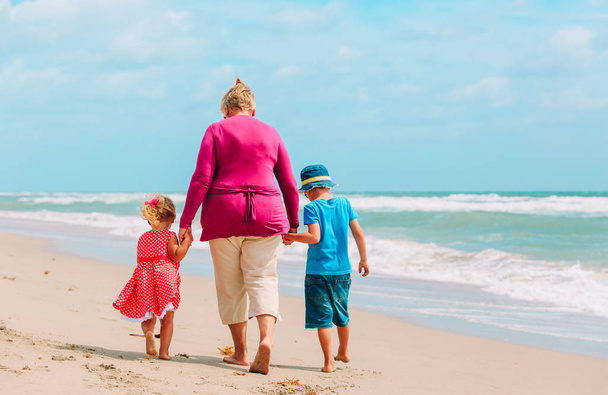 Happy grandmother with kids- little boy and girl- at beach - Photo, Image