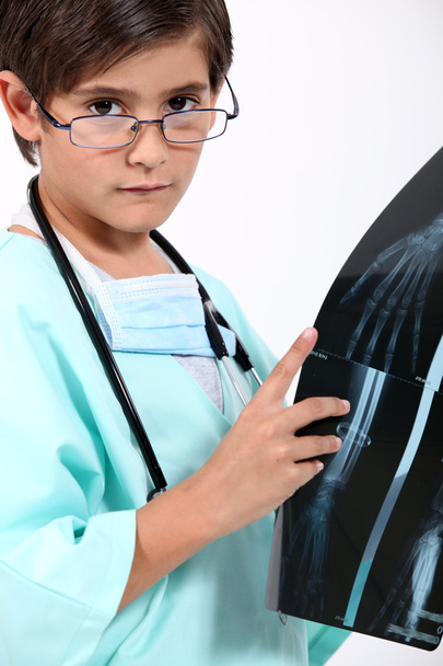 μικρό αγόρι ντυμένος ως γιατρός κοιτάζοντας μια εικόνα ακτινογραφία - Φωτογραφία, εικόνα