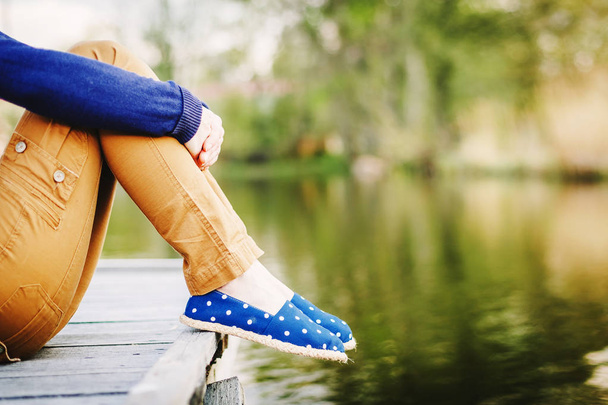 Sitting Woman's feet in a sneakers near the lake - Fotó, kép