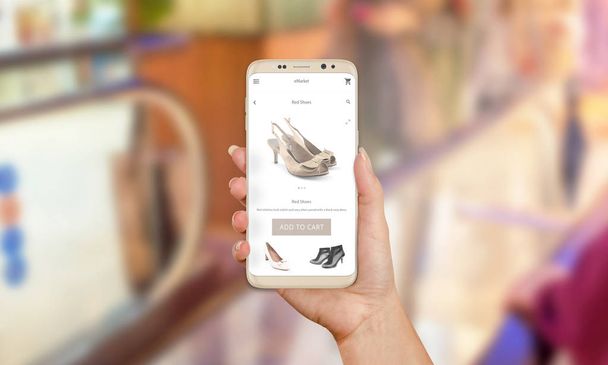 Frau kauft online Schuhe mit Handy-App. Kauf von modernen Schuhen. Jetzt kaufen-Taste auf mobile App. Einkaufszentrum im Hintergrund - Foto, Bild