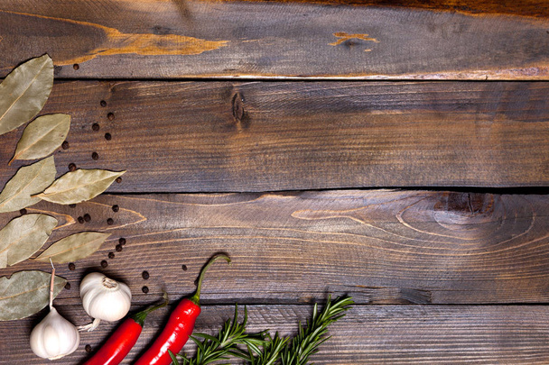 Papryka chili i gałązek rozmarynu z liści laurowych i głowice biały czosnek na podłoże drewniane - Zdjęcie, obraz