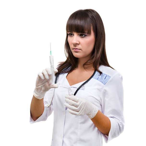 Doctor or nurse in face mask and lab coat holding syringe. Isolated over white. - Fotoğraf, Görsel