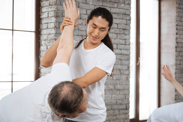 Smiling Asian instructor looking on his client - Foto, Imagen