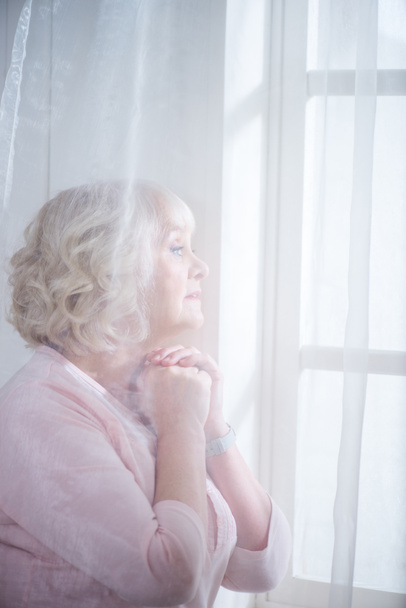 Mujer mayor en la ventana
 - Foto, Imagen