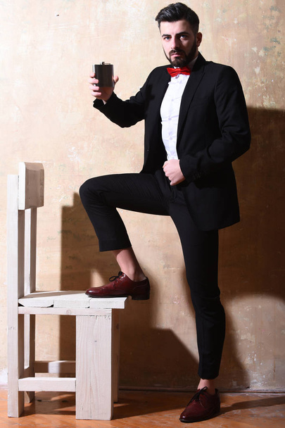 bearded man holding flask with serious face, studio wall background - Φωτογραφία, εικόνα