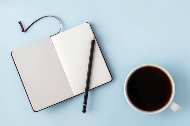 Kancelář modrá tabulka s prázdný Poznámkový blok, tužku a bílý šálek kávy. Prostor pro text kopírovat. Byt leží. Pohled shora. - Fotografie, Obrázek