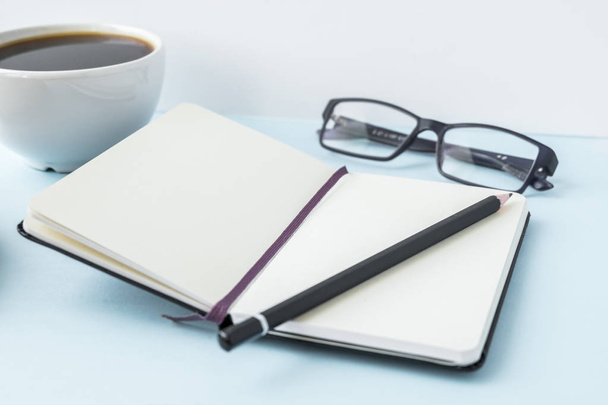 Kancelář modrá tabulka s prázdný Poznámkový blok, tužka, brýle a šálek kávy. Kopírovat prostor pro text. - Fotografie, Obrázek