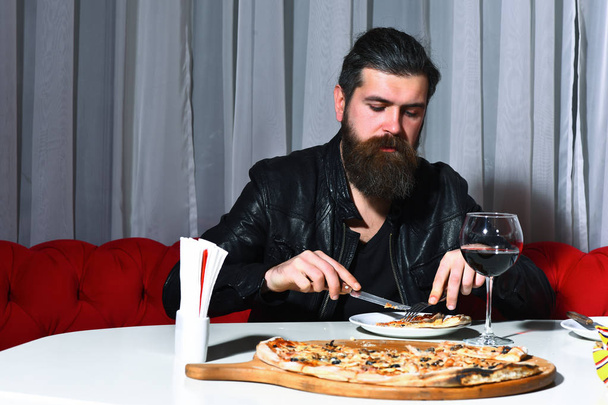 Bearded man eating pizza with knife and fork - Фото, зображення