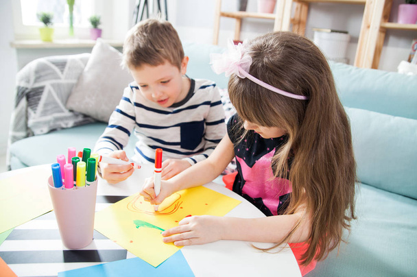 Brother and sister drawing with colorful pencils at home - 写真・画像