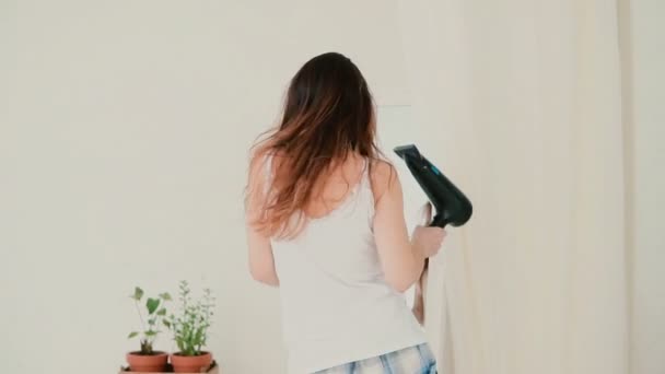 Beautiful young woman feeling happy and singing while using hairdryer. Girl dancing in front of mirror. Slow motion. - Πλάνα, βίντεο
