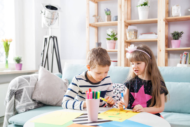 Брат и сестра рисуют разноцветными карандашами дома
 - Фото, изображение