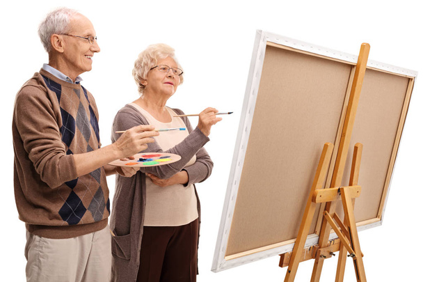 Elderly man and woman painting on a canvas with paintbrushes - Фото, изображение