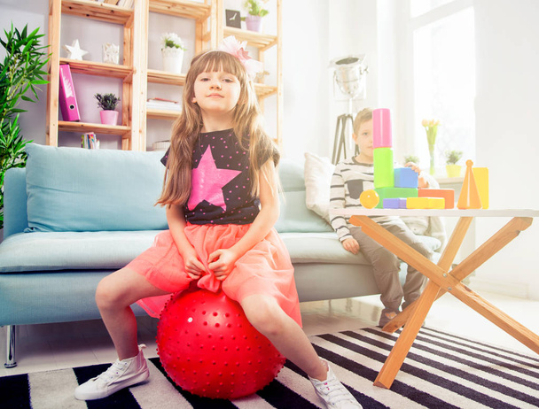 Siblings playing with blocks and fitness ball at home - Foto, imagen