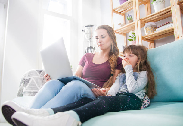 Mother using laptop while daughter is bored, family at home - Φωτογραφία, εικόνα