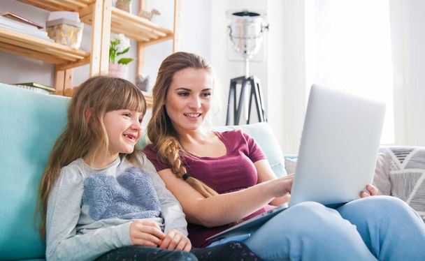 Mother and daughter using laptop together, happy loving family - Фото, изображение