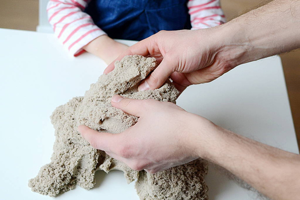 Kız bebek Kinetik kumla oynamak. Babasının ellerini - Fotoğraf, Görsel